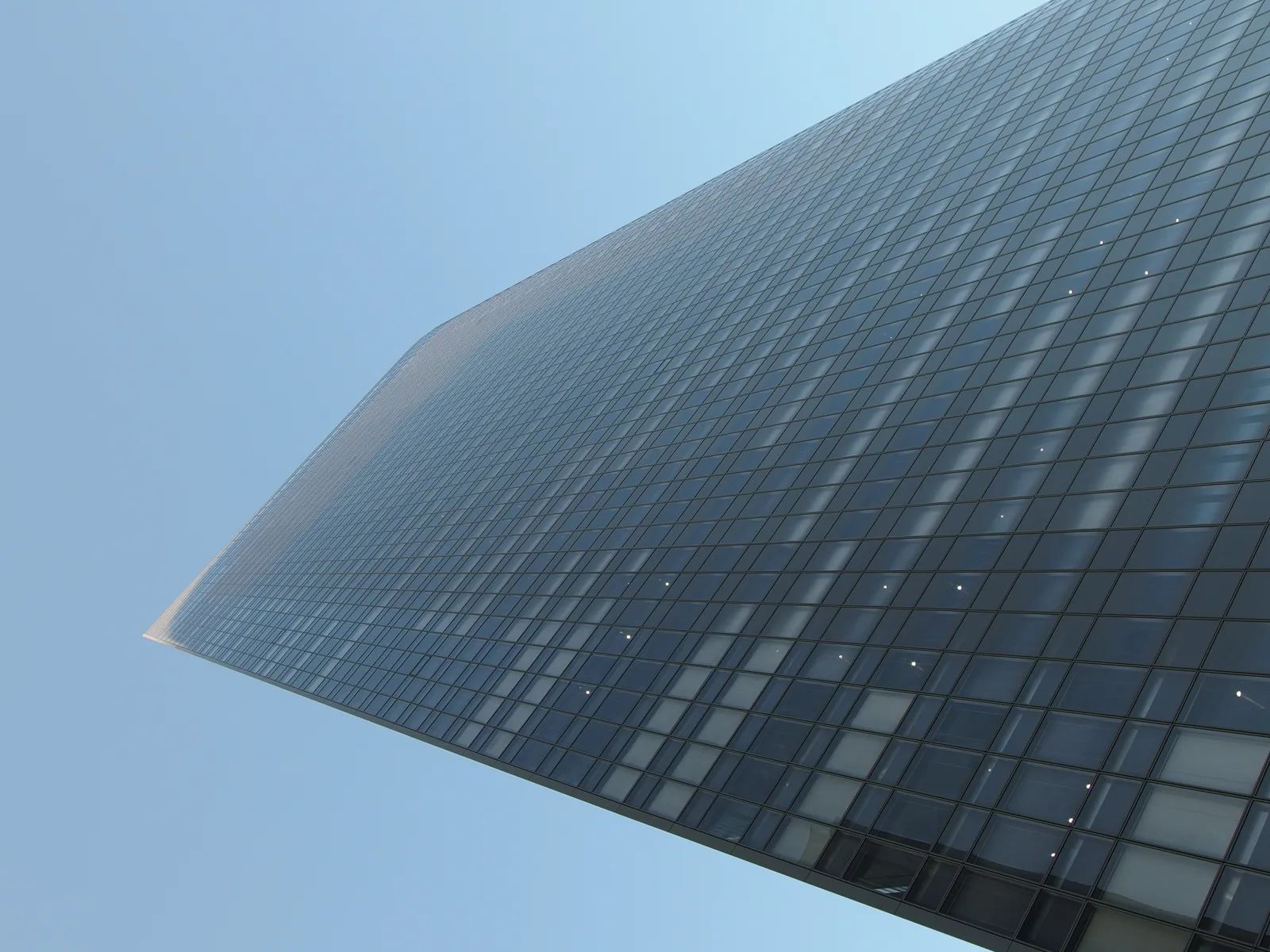 青空にそびえる高層ビルのガラス外観(電通グループ)