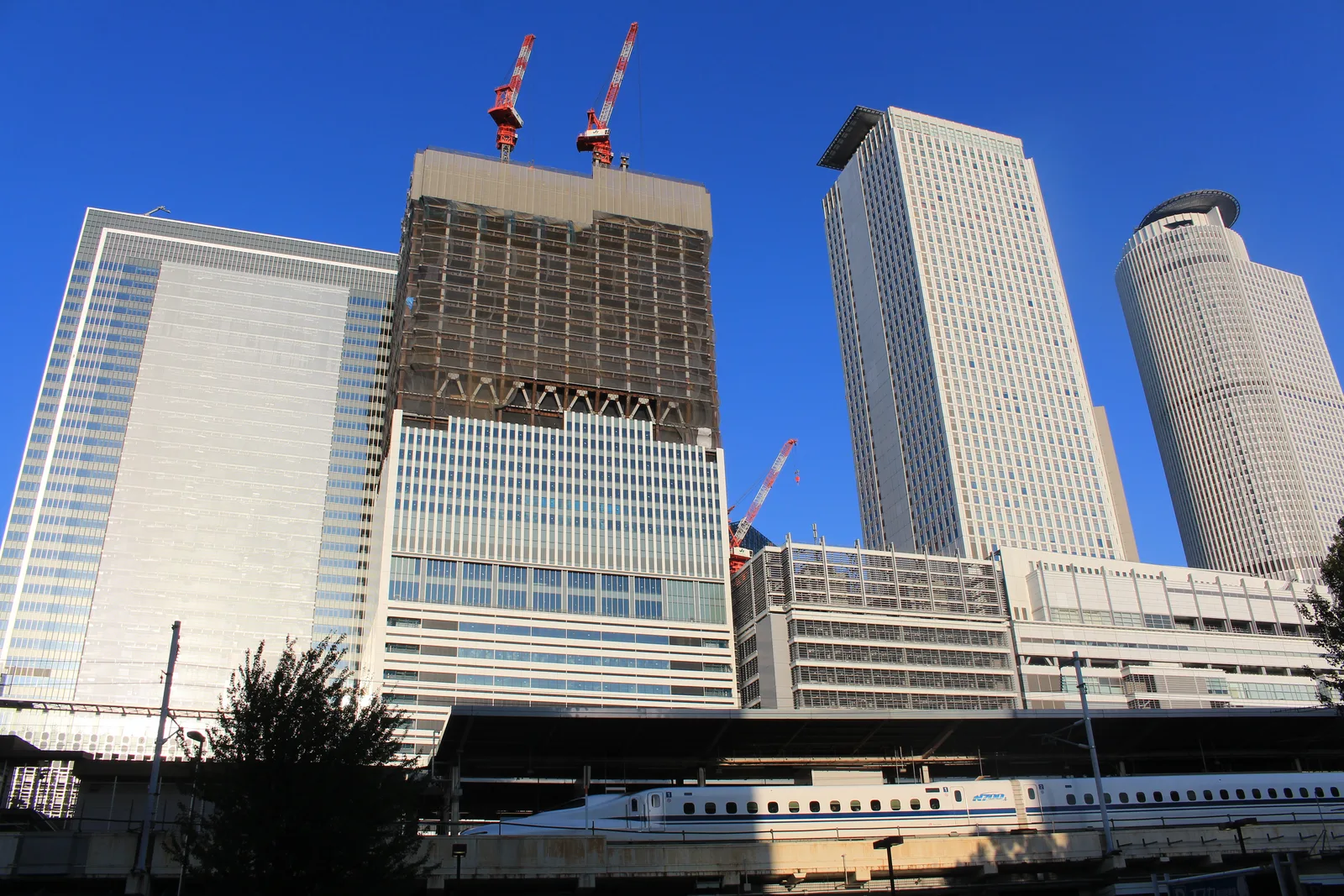 建設中の高層ビル群と新幹線が見える駅前風景（トヨタシステムズ）